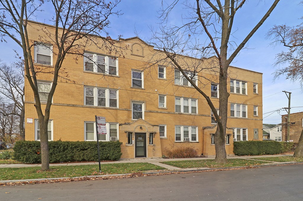 a large brick apartment building on a street with trees