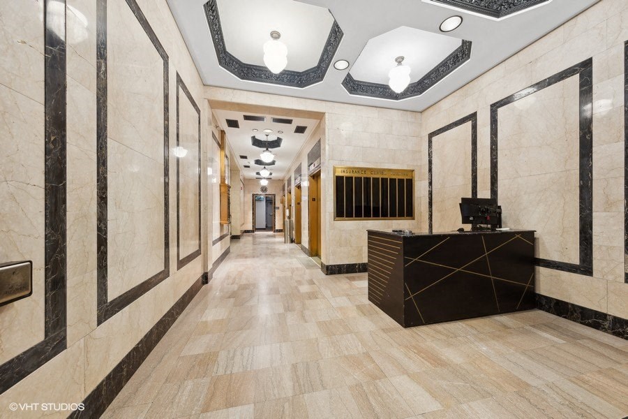 the lobby of a building with a reception desk and a long hallway with marble walls