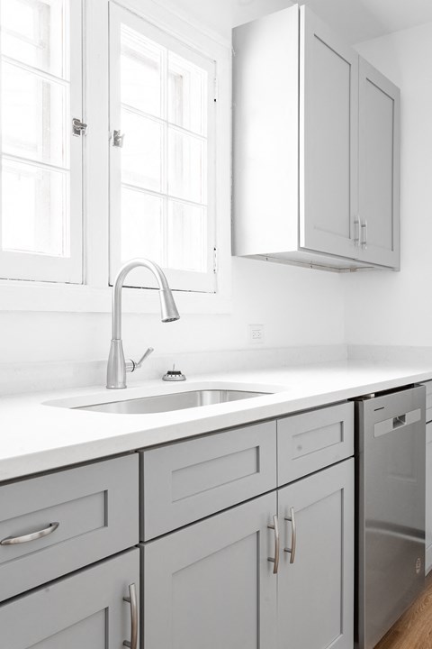 A modern kitchen with a white countertop and grey cabinets.