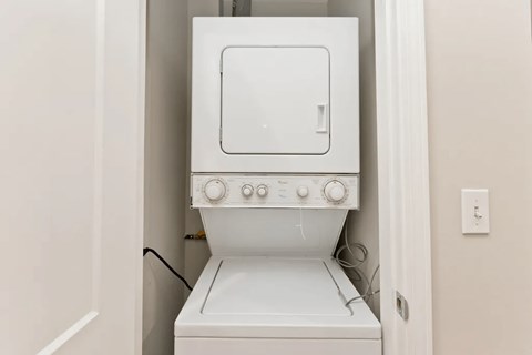 A white washing machine is sitting in a small space.