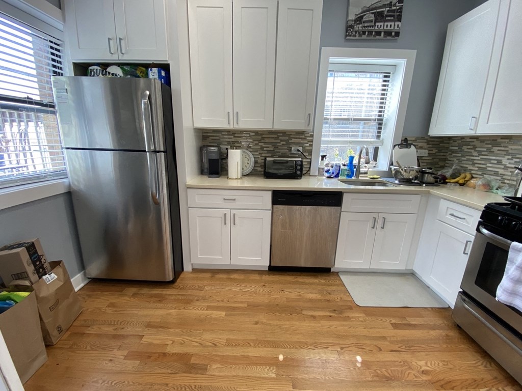 a kitchen with white cabinets and a stainless steel refrigerator