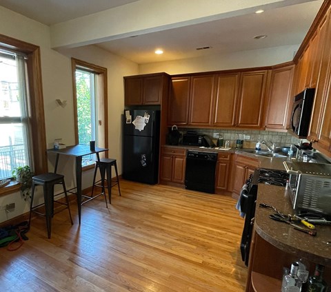 A kitchen with wooden cabinets and a black fridge.
