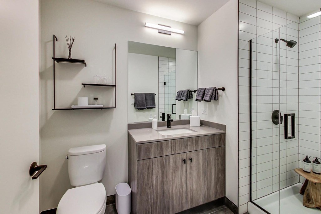 a bathroom with a toilet sink mirror and shower in a 555 waverly unit