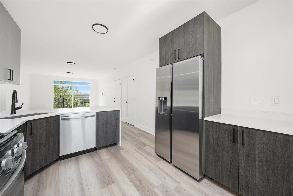 A modern kitchen with a stainless steel refrigerator and wooden cabinets.