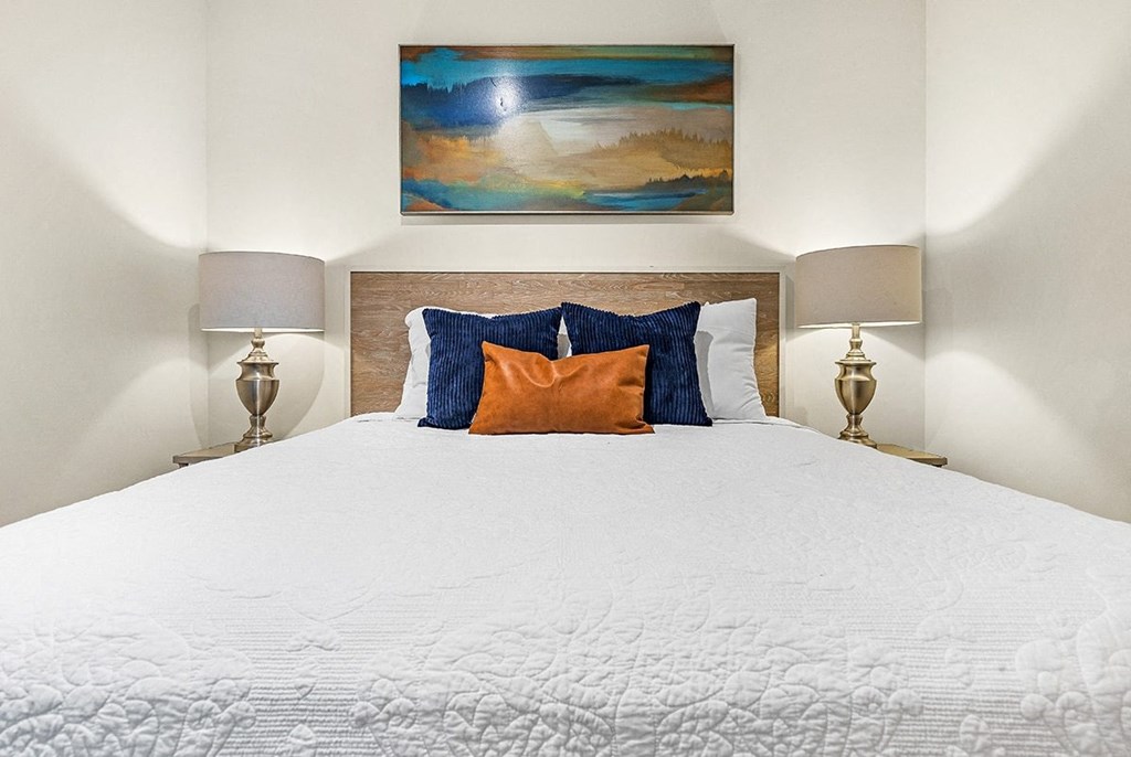 a bedroom with a white bed with blue and orange pillows