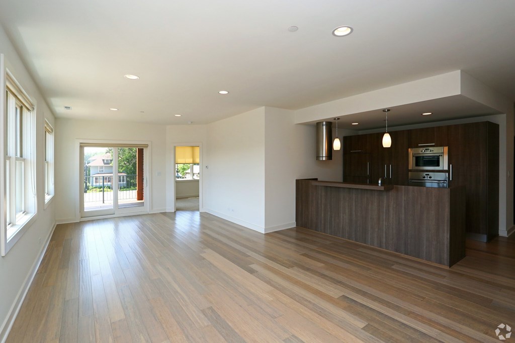 A spacious living room with wooden flooring and a television on the cabinet.