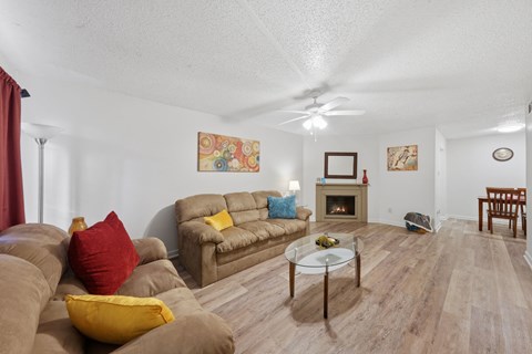 A living room with a brown couch and a glass coffee table.