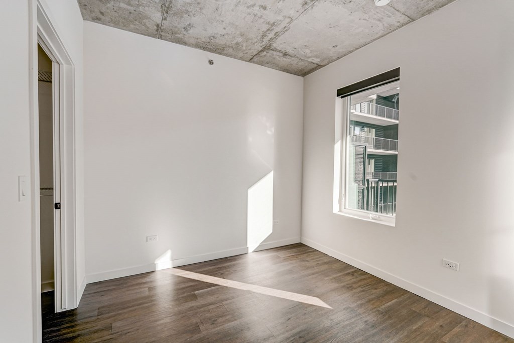 A room with a window and a wooden floor.
