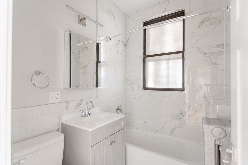 a white bathroom with a sink and tub and a window