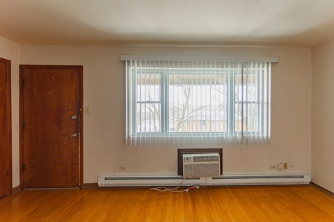 an empty room with a window and a heater on the floor