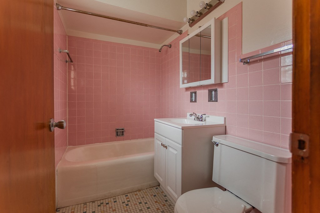 a pink bathroom with a toilet sink and bath tub