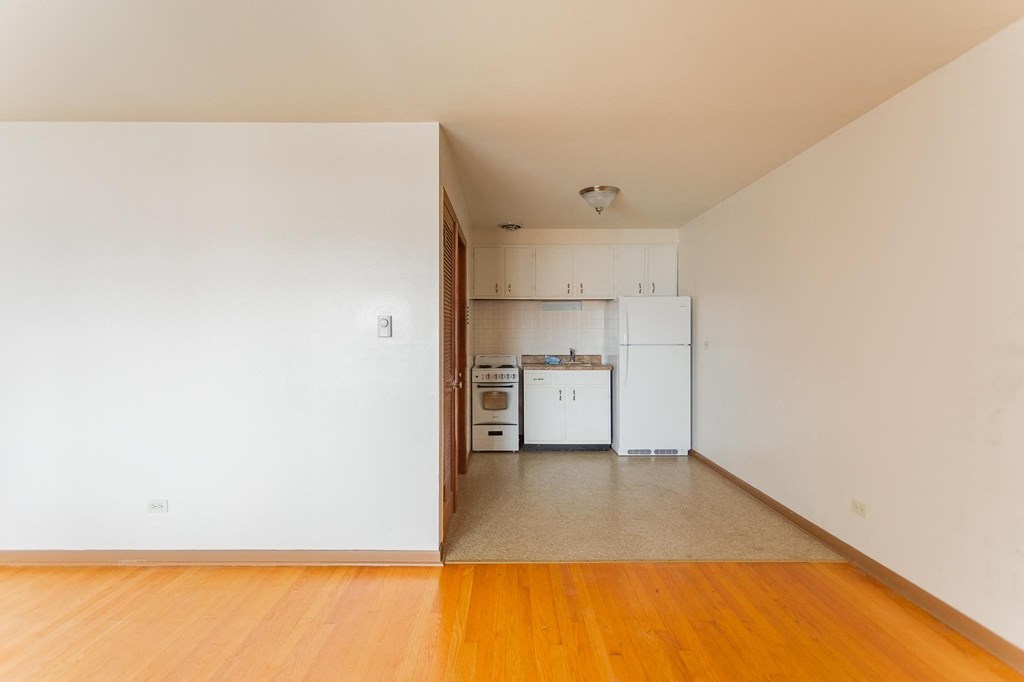 an empty living room and kitchen with white walls and wood floors