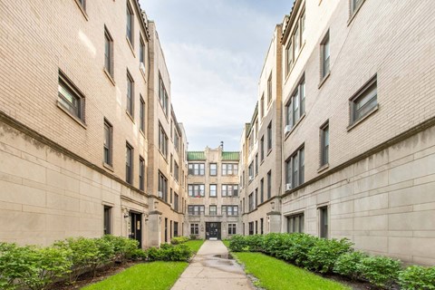 A long, narrow courtyard between two buildings with greenery on the sides.