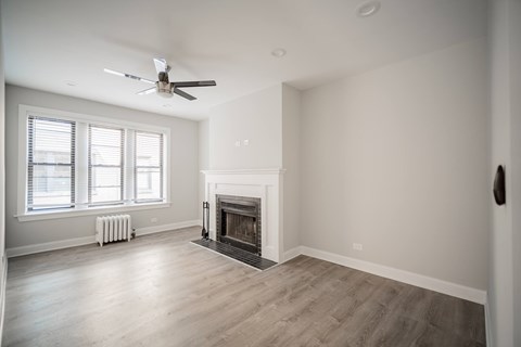 A spacious living room with a fireplace and a ceiling fan.