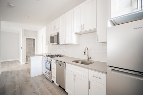 A kitchen with white cabinets and appliances.