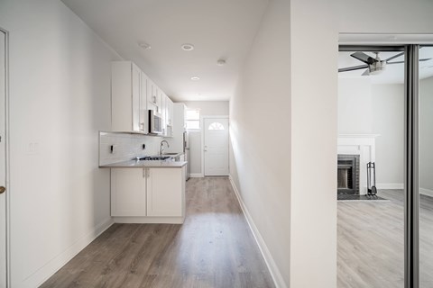 A modern kitchen with white cabinets and a wooden floor.