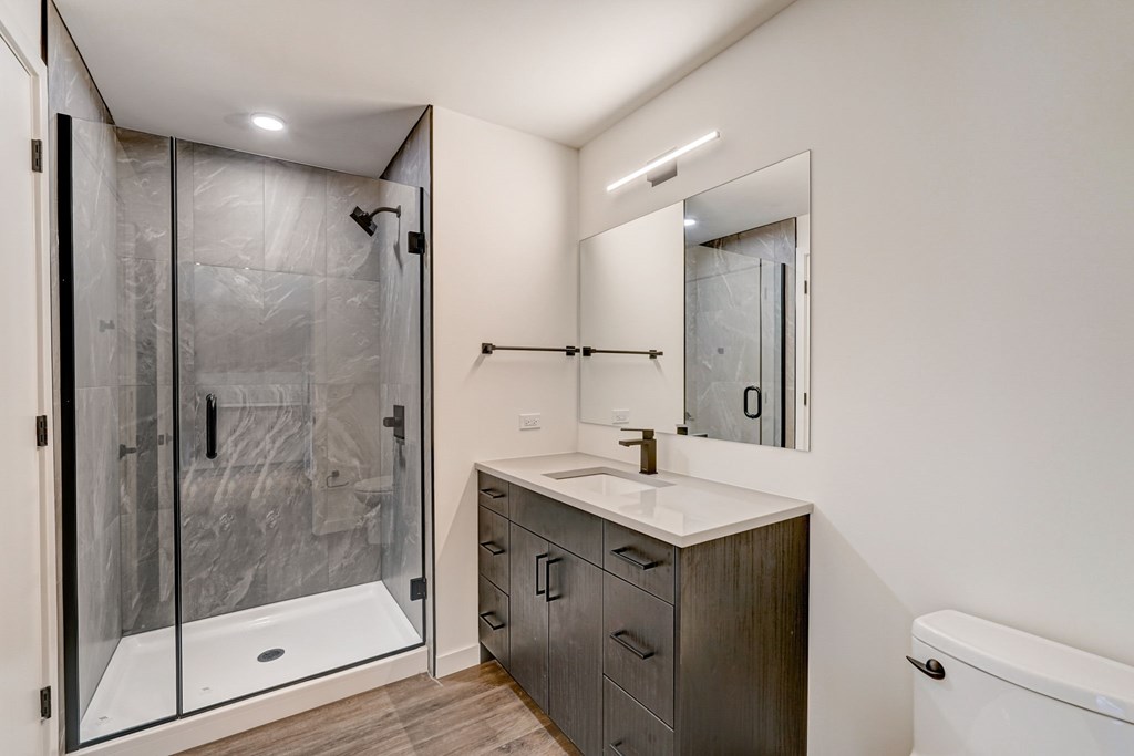 A modern bathroom with a walk-in shower and a white countertop vanity.