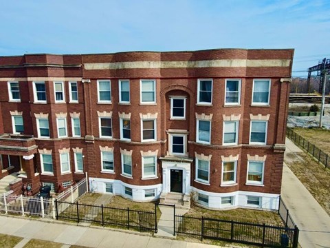 A red brick building with a black fence in front.