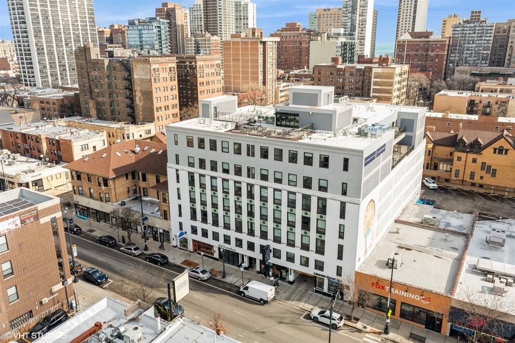 A white building with a blue stripe on the side is in the middle of a city street.