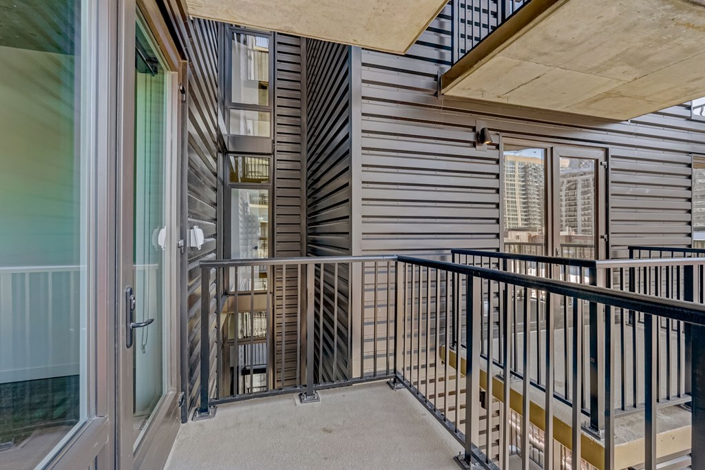 A balcony with a black railing and a glass door.