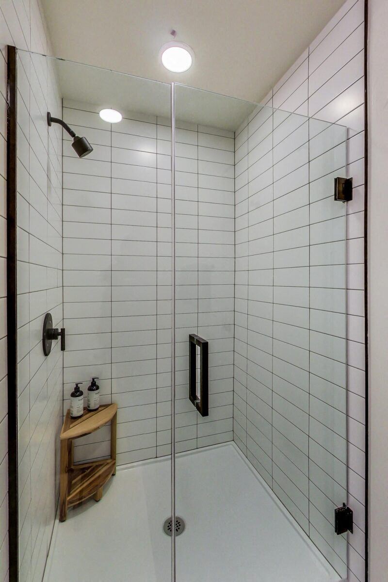 a white tiled shower with black fixtures