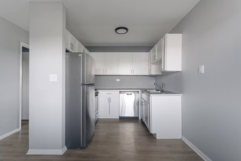 A modern kitchen with white cabinets and a grey refrigerator.