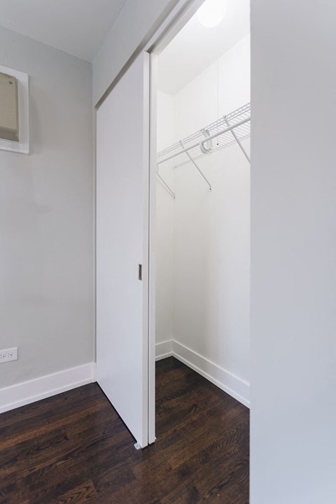 a bedroom with white walls and a closet with a mirrored door