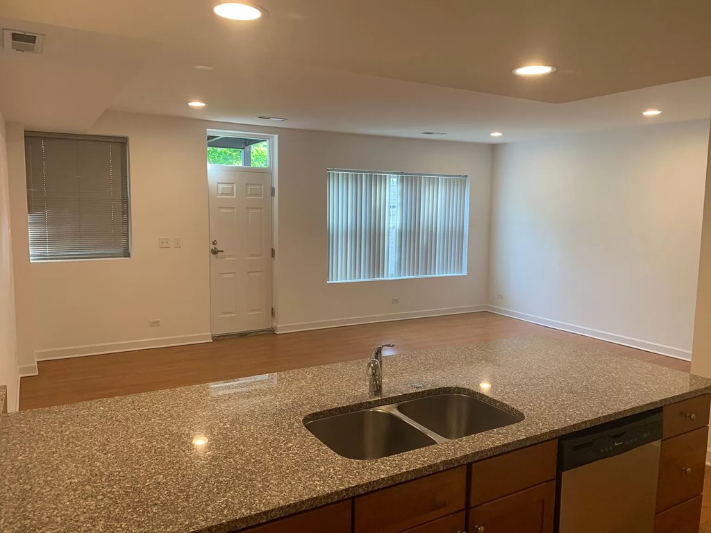 an empty kitchen with a granite counter top and a sink