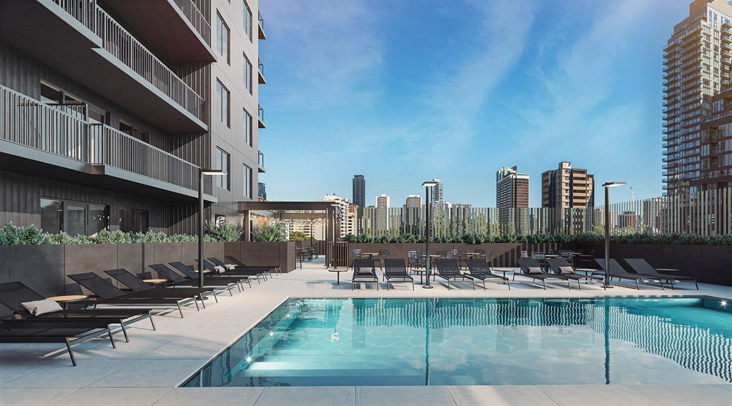 an outdoor pool with lounge chairs and a view of the city