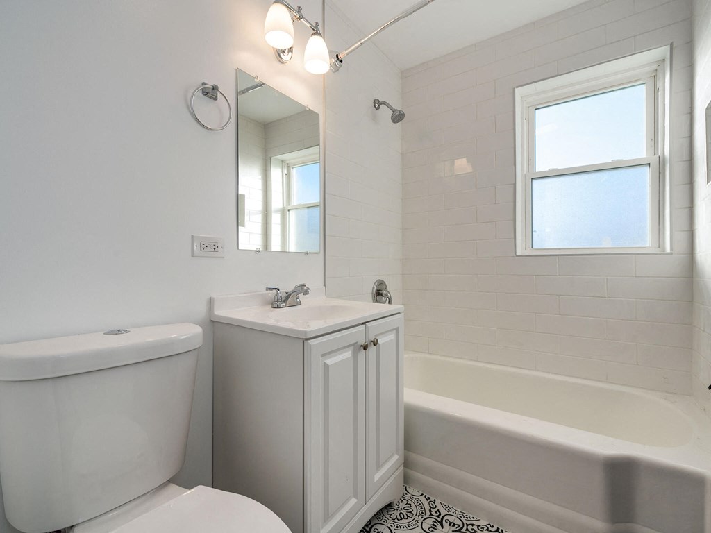 A white bathroom with a tub, toilet, sink, and mirror.