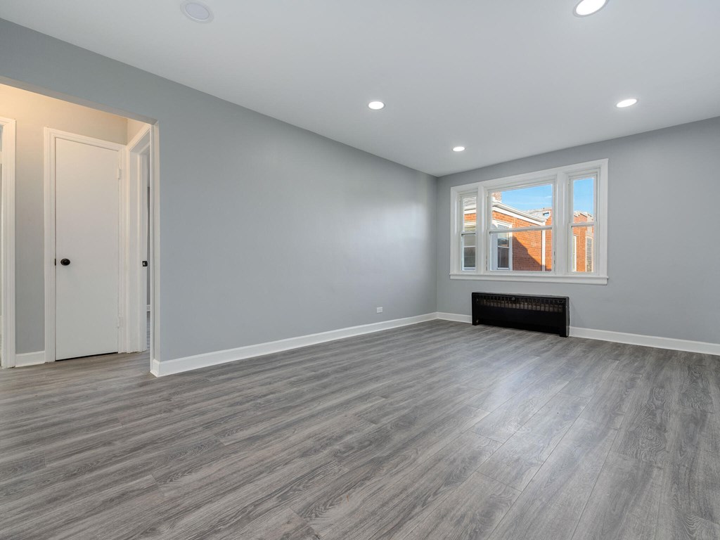A room with grey walls and a window showing a building outside.