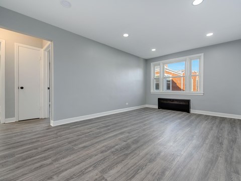 A room with grey walls and a window showing a building outside.