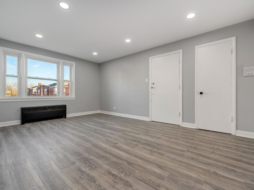 A room with grey walls and wooden flooring with two white doors.