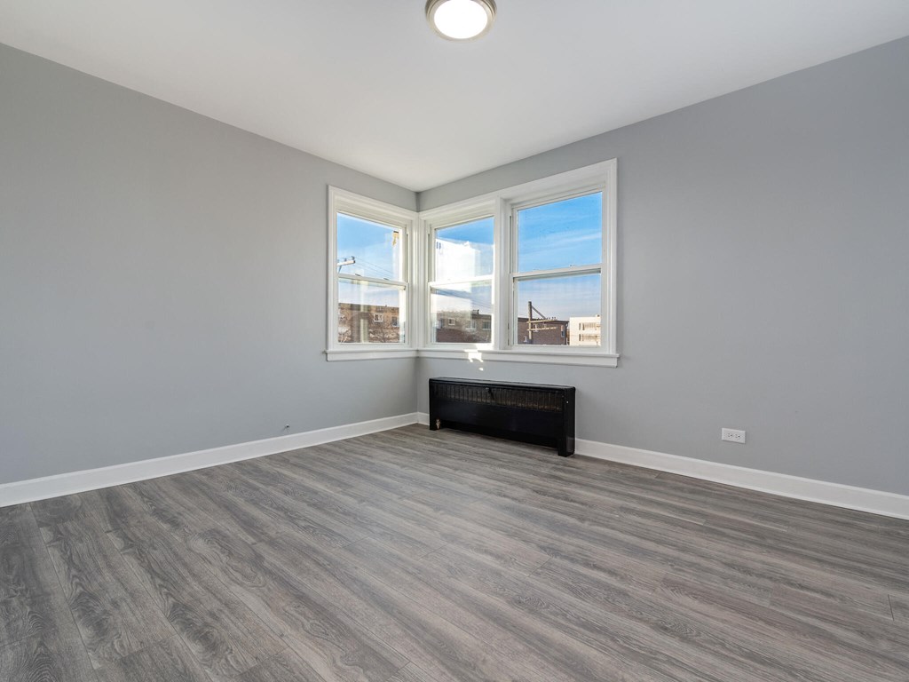 A room with grey walls and a wooden floor with a large window.