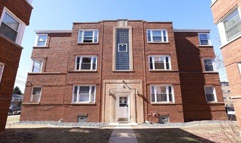 A red brick building with a central entrance and windows on each floor.