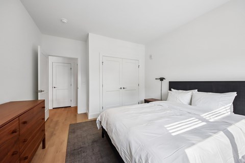 A bedroom with a large bed and a wooden dresser.