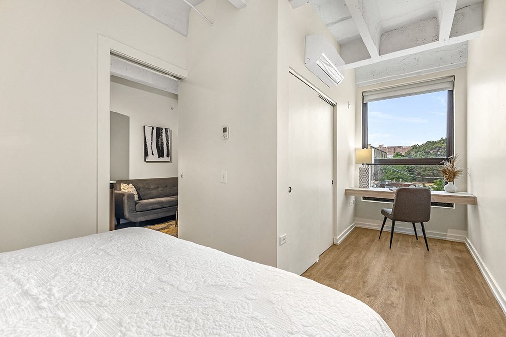 a bedroom with a bed and a desk and a window