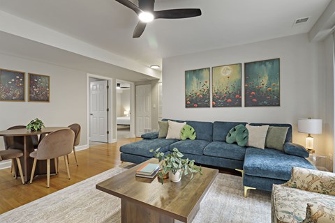 A living room with a blue couch and a ceiling fan.