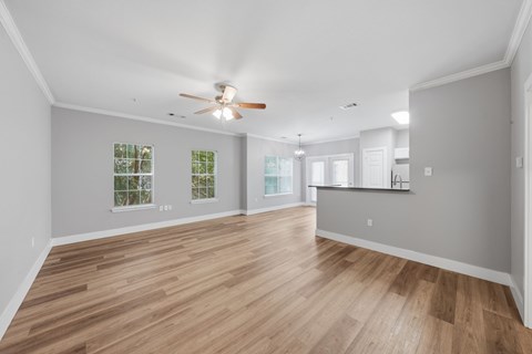 A spacious room with wooden flooring and a ceiling fan.