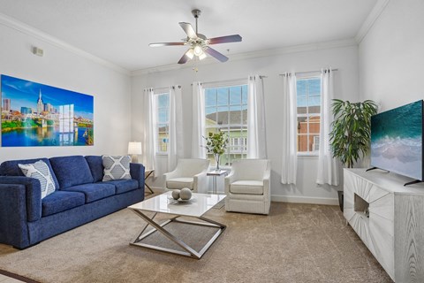 A living room with a blue couch, a white chair, a coffee table, and a painting on the wall.