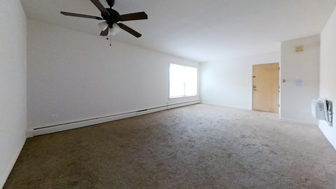 A room with a ceiling fan and carpeted floor.