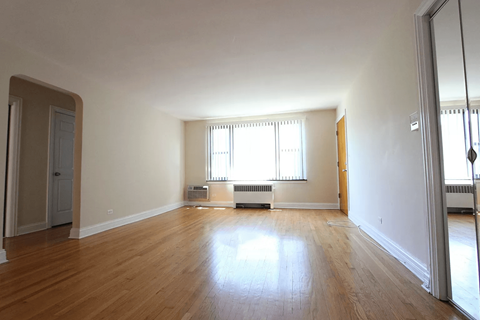 A large empty room with wooden floors and white walls.