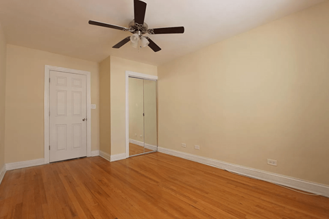A room with a ceiling fan and wooden floors.