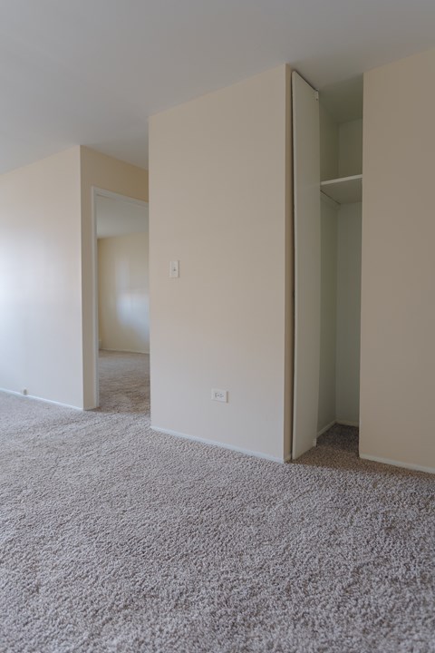 A room with carpeted floor and white walls with a doorway open.