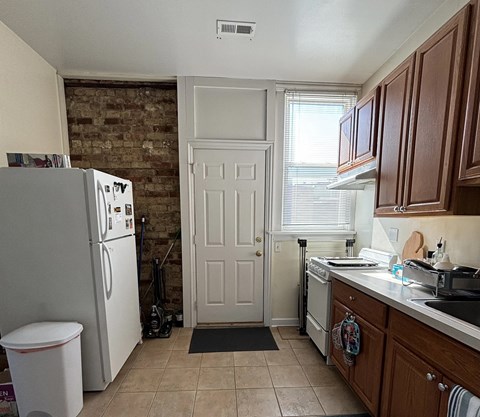 A kitchen with a white refrigerator and wooden cabinets.