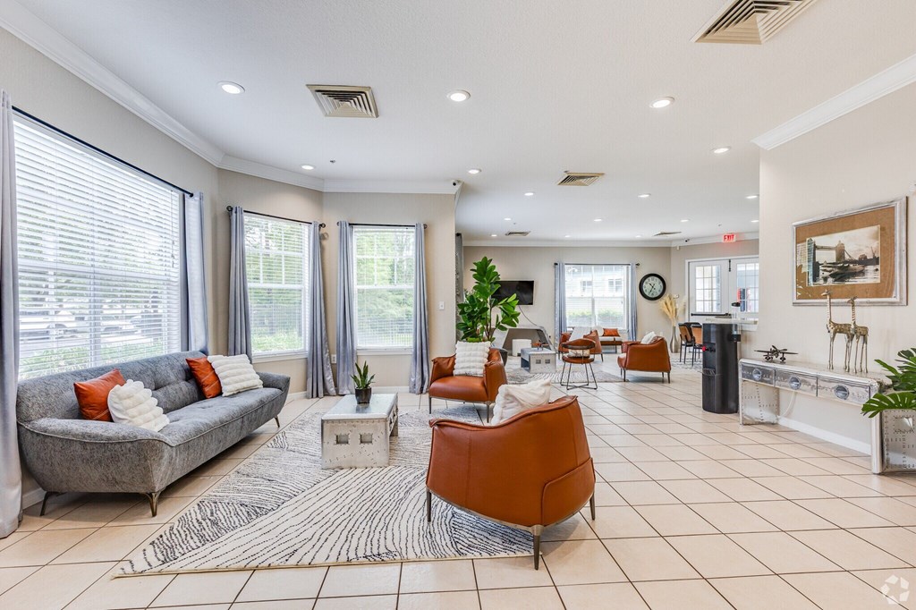 A living room with a grey couch, orange chairs, and a white coffee table.