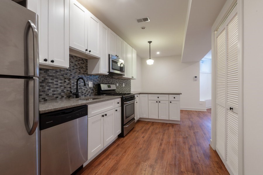 A kitchen with white cabinets and a wooden floor.
