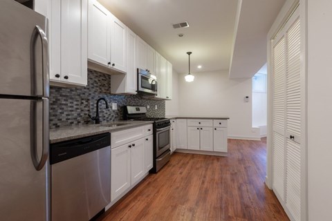 A kitchen with white cabinets and a wooden floor.