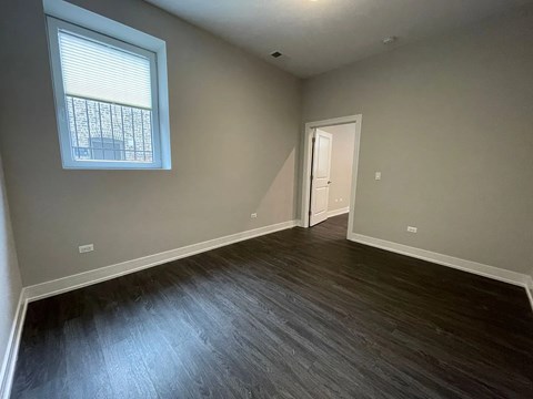 A room with a wooden floor and a window with blinds.