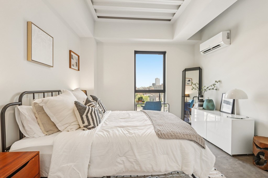 A bedroom with a large bed and a window overlooking a cityscape.